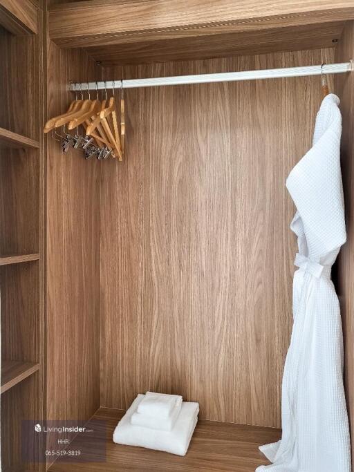 Spacious wooden walk-in closet with bathrobe and towels