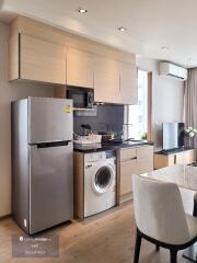 Modern kitchen with appliances including refrigerator, washing machine, and microwave