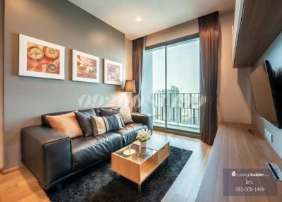 Modern living room with black leather sofa, wooden coffee table, wall-mounted TV, and city view from the balcony