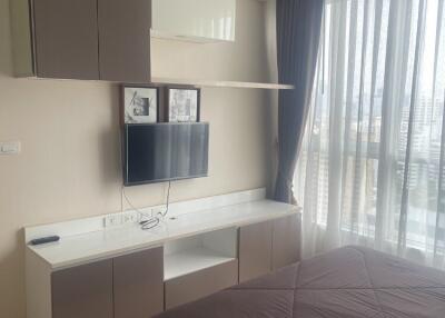 Modern bedroom with TV, storage cabinets, and a large window