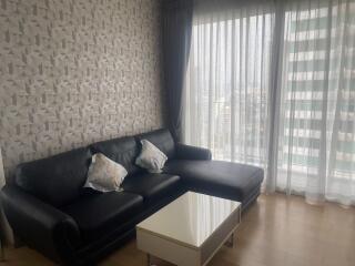 Living room with a black leather sofa, modern wallpaper, and a small coffee table