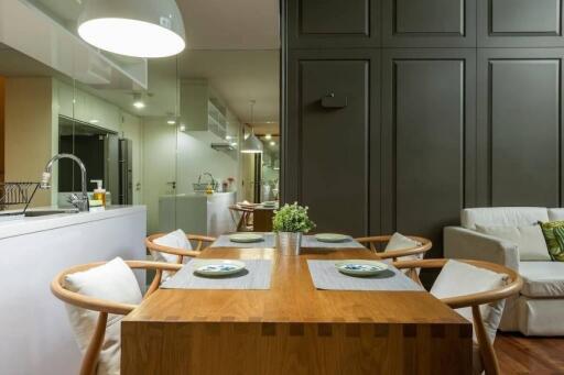 Modern dining area with wooden table and chairs, adjacent to the kitchen.