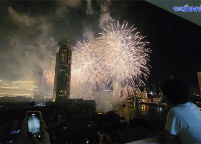 A view of fireworks over a city skyline as seen from a balcony.