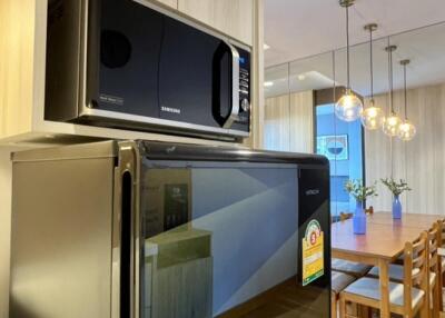 Modern kitchen corner with fridge and microwave, view towards dining area