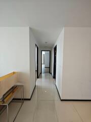 Bright hallway with white tiles leading to multiple rooms