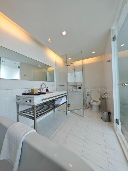 Modern bathroom with large mirror, vanity, shower, and toilet