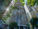 Exterior view of a modern apartment building with tall structure and surrounding greenery