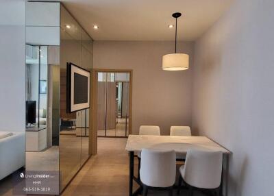 Modern dining area with table and chairs, mirrored wall panels, and pendant light