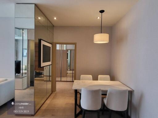 Modern dining area with table and chairs, mirrored wall panels, and pendant light