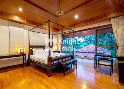 Spacious wooden-themed bedroom with canopy bed and large windows