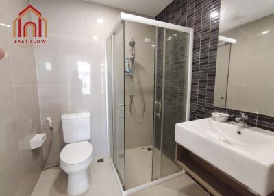 Modern bathroom with glass shower, toilet, and washbasin