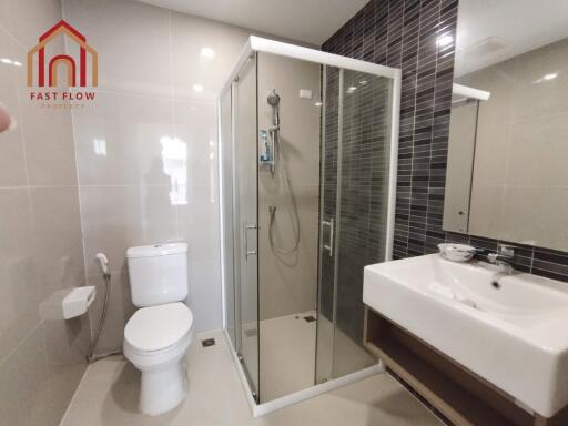 Modern bathroom with glass shower, toilet, and washbasin