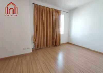 Empty bedroom with wooden flooring and window with beige curtains