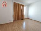 Empty bedroom with wooden flooring and window with beige curtains