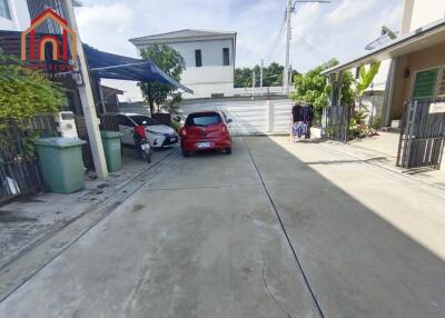 Driveway entrance with parked cars and surrounding houses.