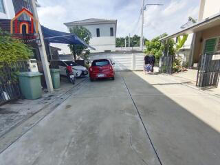 Driveway entrance with parked cars and surrounding houses.