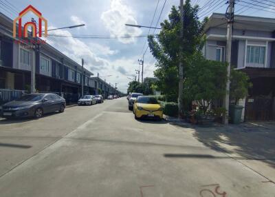 Photo of the residential street featuring multiple modern townhouses and parked cars.