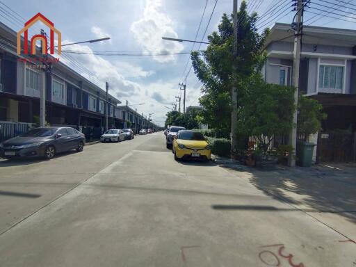 Photo of the residential street featuring multiple modern townhouses and parked cars.