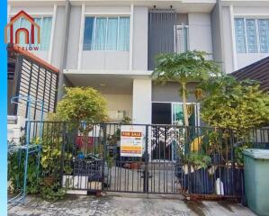 Exterior view of a modern townhouse with a for sale sign