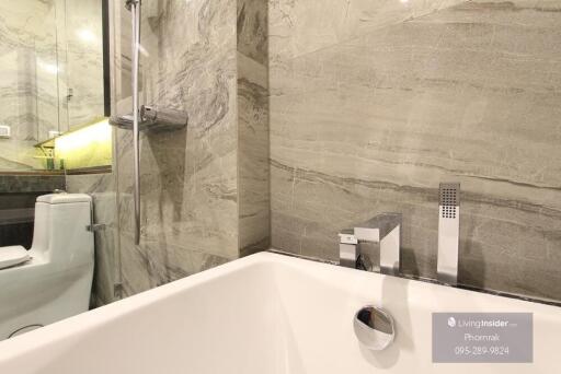 Modern bathroom with marble walls, bathtub, and fixtures