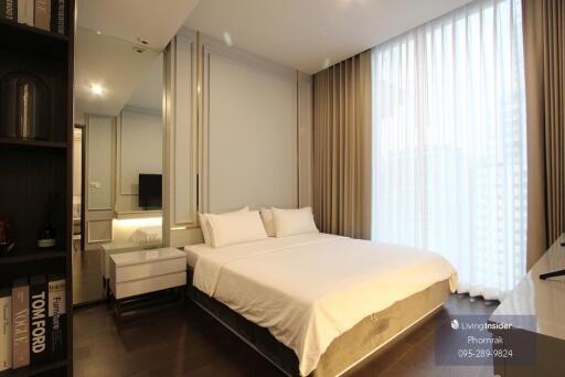 Modern bedroom with double bed, large window with sheer curtains, and built-in storage