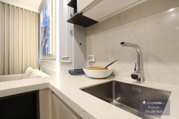 Modern kitchen with white countertop, stainless steel sink, and decorative elements