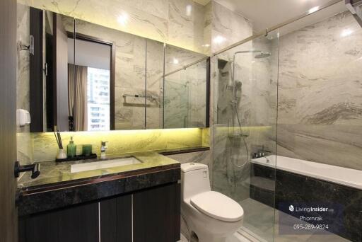 Modern bathroom with marble walls, glass shower, and black countertop