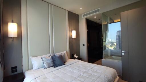 Modern bedroom with city view and glass-enclosed bathroom