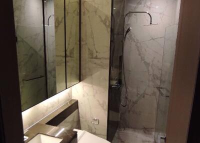 Modern bathroom with marble tiles, glass shower enclosure, and large mirror