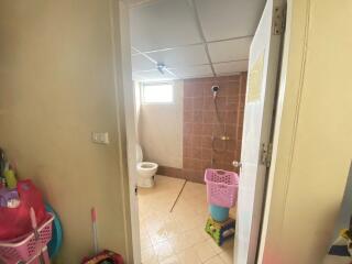 View into a bathroom with tiled walls and floor, showing a toilet and shower area