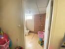 View into a bathroom with tiled walls and floor, showing a toilet and shower area