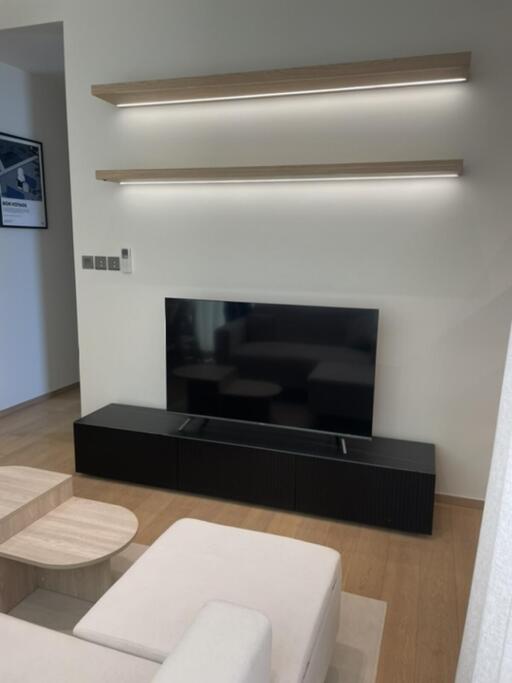 Modern living room with mounted shelves and a television on a low console