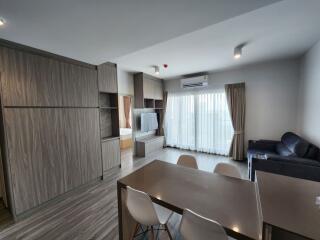 Modern living area with dining table, chairs, couch, TV, and large windows