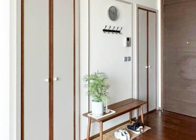 A modern entryway with wooden flooring, and a minimalist design bench with storage space.