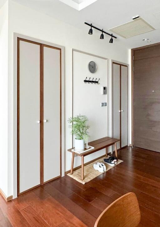 A modern entryway with wooden flooring, and a minimalist design bench with storage space.