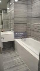 Modern bathroom with gray marble tiles, bathtub, and a sink