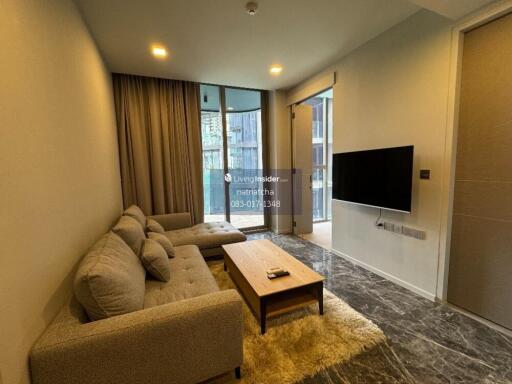 Modern living room with sofa, wall-mounted TV, and floor-to-ceiling window