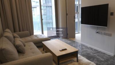 Living room with a sofa, coffee table, wall-mounted TV, and large windows