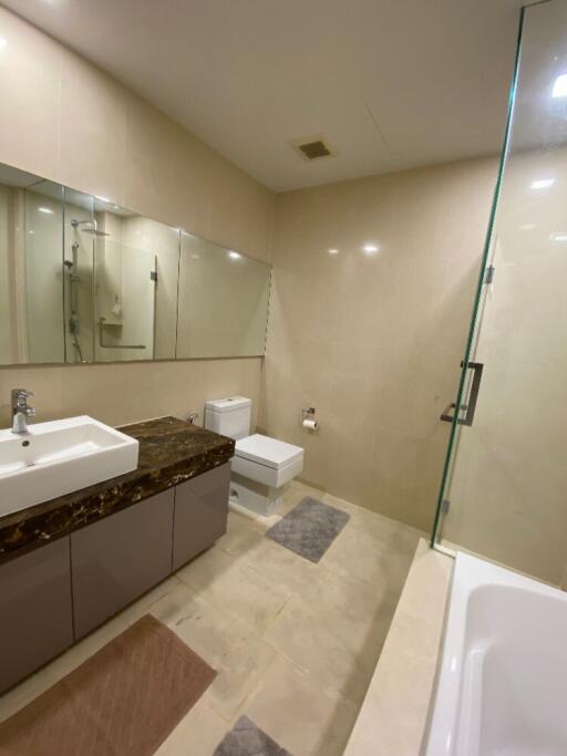 Modern bathroom with large mirror, sink, toilet, and glass-enclosed shower