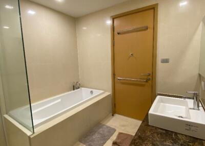 Modern bathroom with bathtub, sink, and wooden door