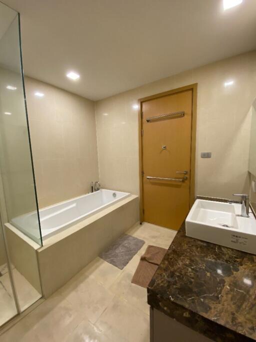 Modern bathroom with bathtub, sink, and wooden door