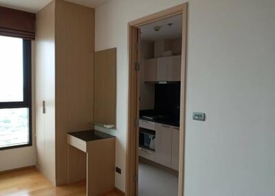 A bedroom with a view into a modern kitchen