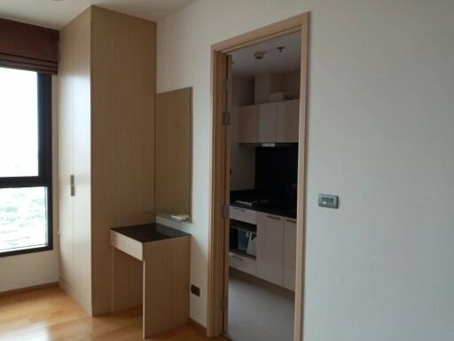 A bedroom with a view into a modern kitchen