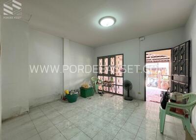 Spacious empty living room with tiled floor, large windows and door to the outside.