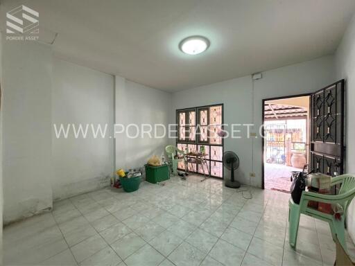 Spacious empty living room with tiled floor, large windows and door to the outside.