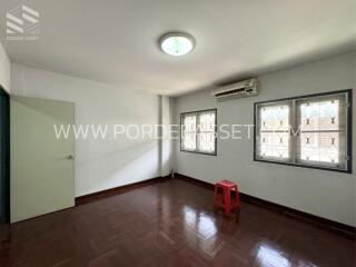 Bright bedroom with wooden flooring, ceiling light, air conditioning, and simple furnishing