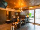 Modern home office with desk, chair, TV, and large glass door opening to a patio