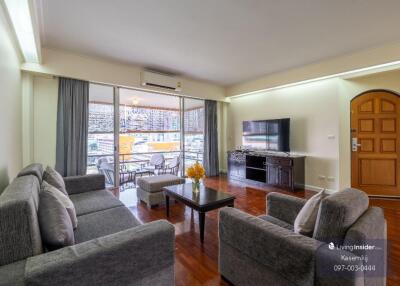 Modern living room with a view, featuring comfortable sofas, a large flat-screen TV, and a wooden coffee table.