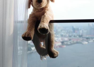 Plush toy on window ledge with city view