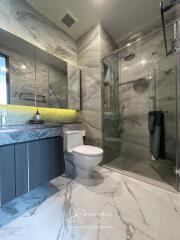 Modern bathroom with marble floor and wall, glass shower enclosure, and large mirror